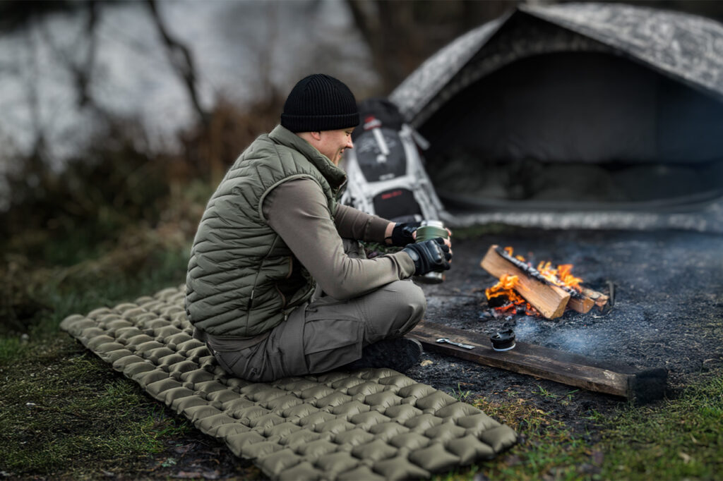 mężczyzna przy ognisku siedzi na macie